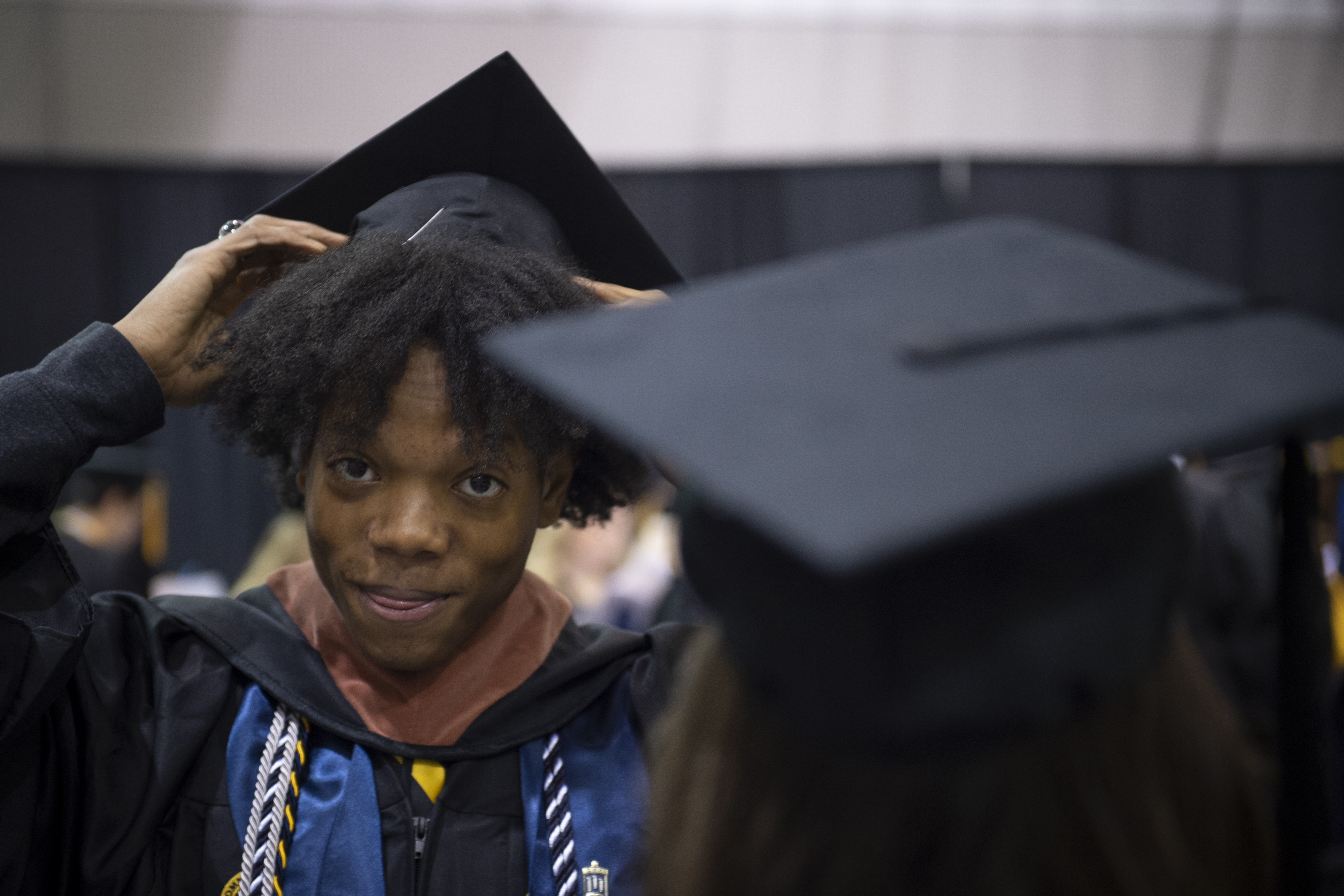 A student straightens his cap at graduation